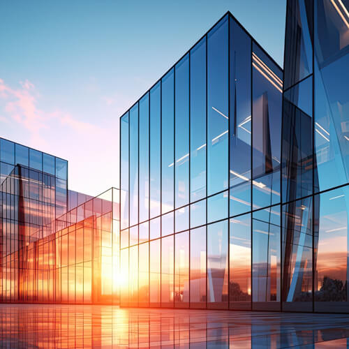 Contemporary office structure with large glass windows highlighting a vibrant sunset