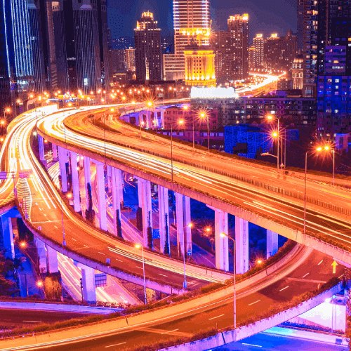 A vibrant cityscape at night illuminated by traffic lights and bustling highways under a starry sky