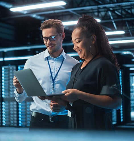 Two people examining a laptop in a server room