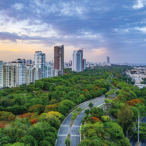 Scenic view of Santo Domingo, Dominican Republic, showing a cityscape with tall buildings and a green park with a road winding through it