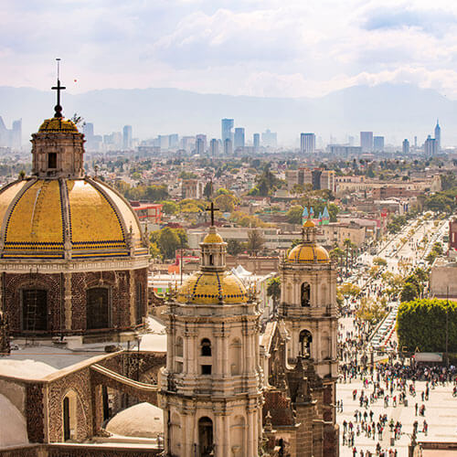 The Basilica of Our Lady of Guadalupe in Mexico City, with its golden domes and the bustling city skyline