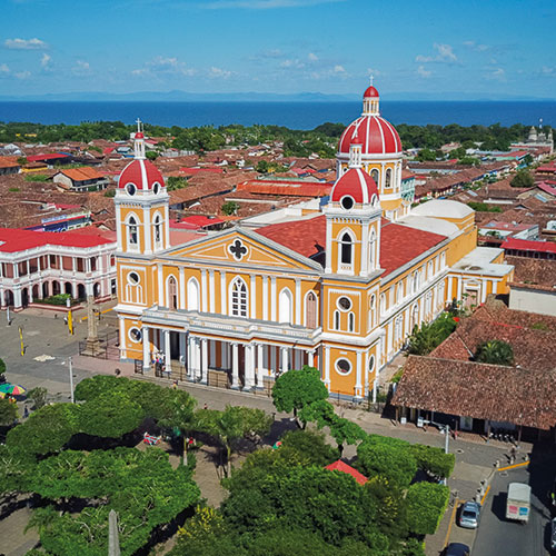 Aerial view of the Granada Cathedral in Nicaragua with its iconic orange and red facade surrounded by colonial-style buildings