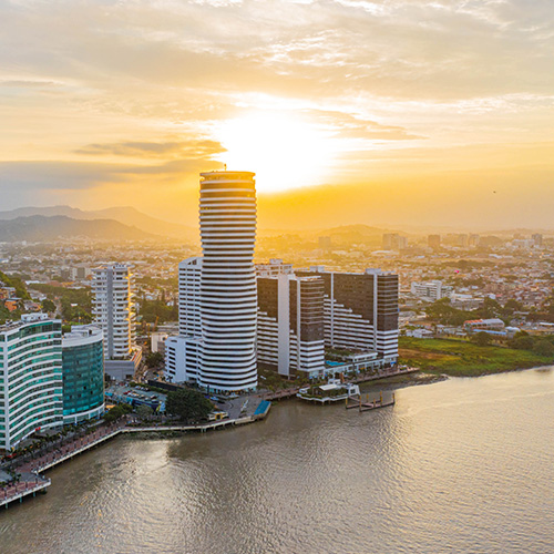 An aerial view of Guayaquil skyline at sunset with the Malecón 2000 promenade and the Guayas River in the foreground