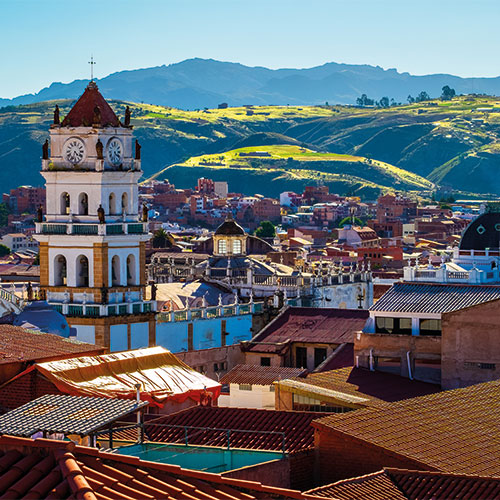 The historic city center of Sucre Bolivia with the iconic clock tower and the Andes Mountains in the background