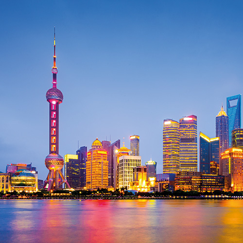 A panoramic view of the Bund skyline in Shanghai, China, at night, with the Oriental Pearl Tower illuminated