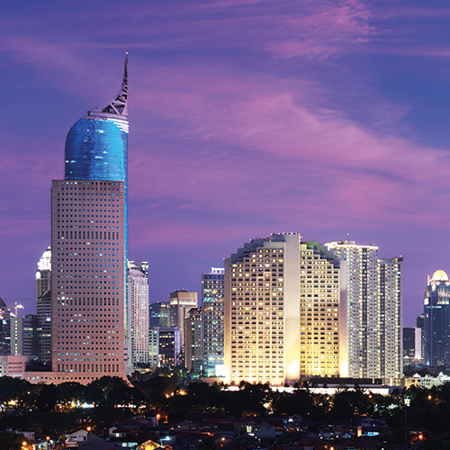 A scenic view of Jakarta skyline at night with illuminated skyscrapers and a purple sky