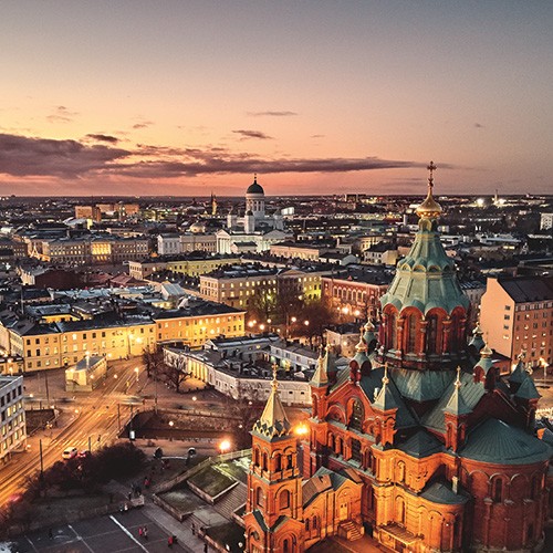 A stunning aerial shot of Helsinki, Finland, showcasing the Uspenski Cathedral and the city's cityscape bathed in the golden light of sunset