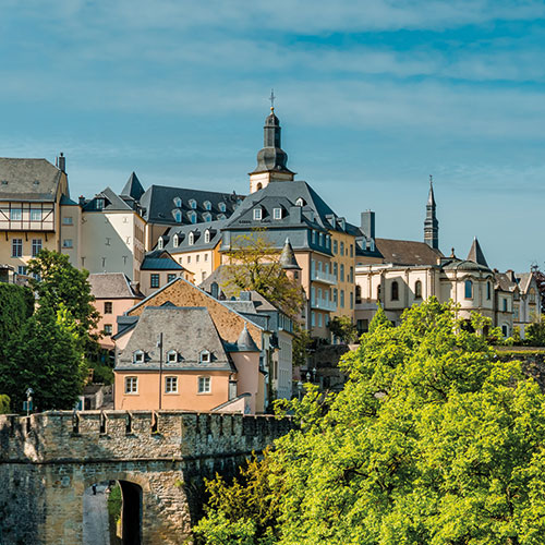 A panoramic view of Luxembourg City, showcasing the historic Grund district and the modern skyline in the background