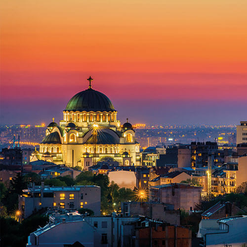 A stunning sunset shot of Belgrade, Serbia featuring the Temple of Saint Sava illuminated against the city skyline