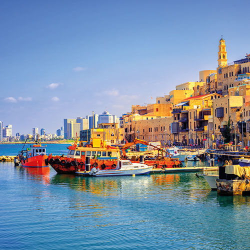 An aerial view of colorful buildings of Jaffa Port, Tel Aviv, Israel overlooking the Mediterranean Sea with boats docked in the harbor