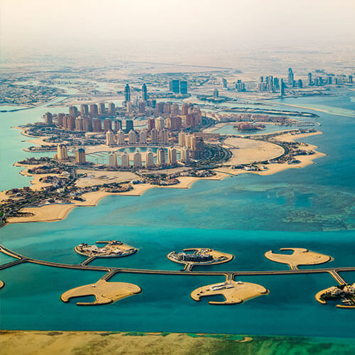 An aerial view of Doha, Qatar, showcasing the city's modern skyline, artificial islands, and the Arabian Gulf