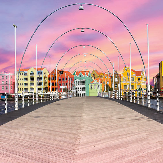 A stunning shot of the Queen Emma Bridge in Willemstad, Curaçao, with colorful buildings lining the waterfront