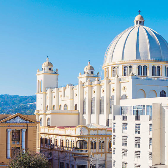 A shot of the Metropolitan Cathedral of San Salvador, a white church with a prominent dome, against a clear blue sky