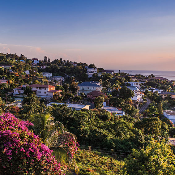 A view of Kingston, Jamaica, with colorful houses on a hillside overlooking the ocean at sunset