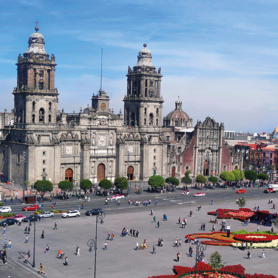 A view of the Mexico City Metropolitan Cathedral, a large, ornate church with twin towers, standing in the Zocalo square