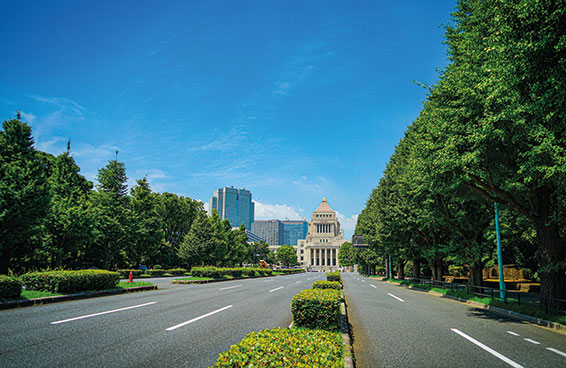 A shot of wide avenue lined with trees leading to the National Diet Building in Chiyoda, Tokyo, Japan under a bright blue sky