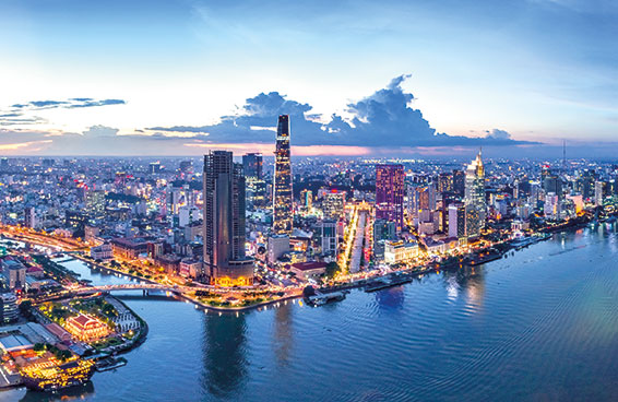 An aerial view of the Ho Chi Minh City skyline at twilight, with the Saigon River flowing through the city