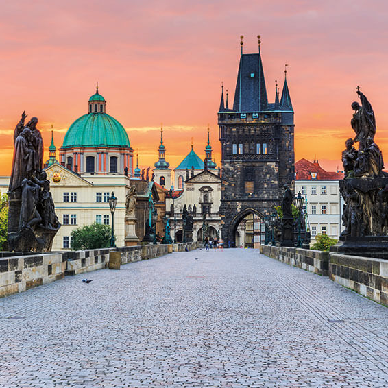 Sunset view of Charles Bridge in Prague with the Old Town Bridge Tower and St. Nicholas Church