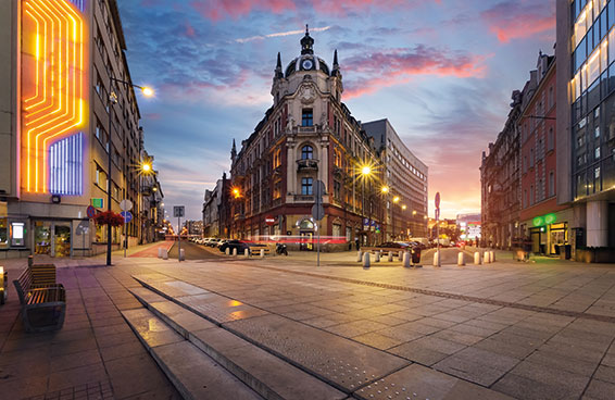 A street in Poznań, Poland, with a historic building illuminated at dusk