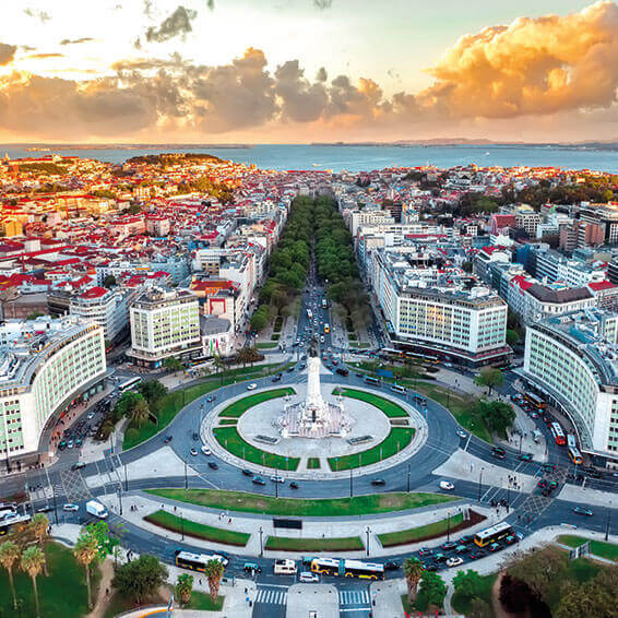 An aerial view of Praça do Comércio in Lisbon, Portugal at sunset, with the Tagus River in the background