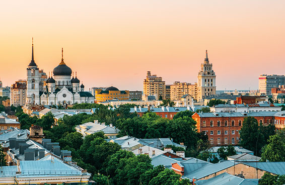 A cityscape of Voronezh, Russia, with several churches and buildings visible at sunset