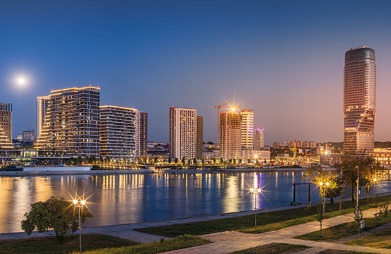 An aerial view of Belgrade Waterfront at dusk, with the Sava River in the foreground