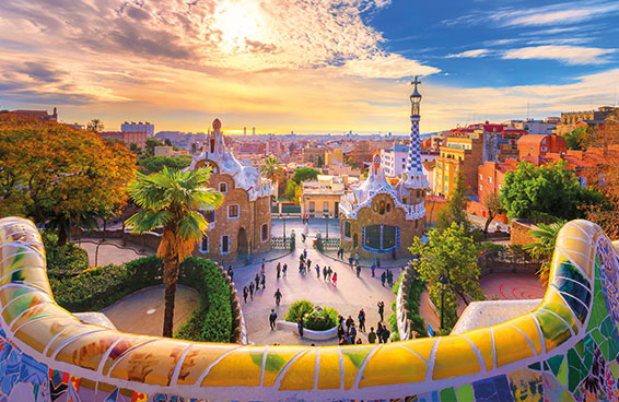 A view of Park Güell in Barcelona, with the iconic mosaic benches and colorful buildings in the background