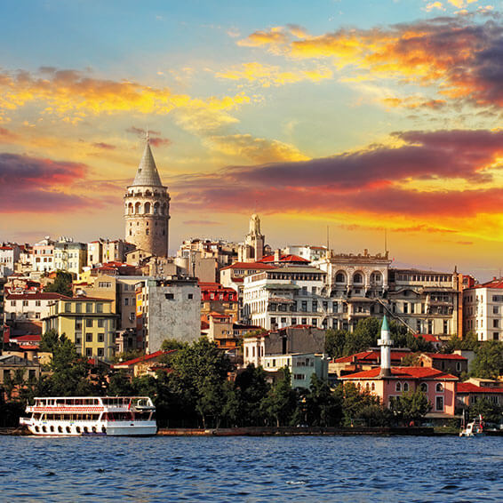 A view of Istanbul, Turkey, with the Galata Tower, historic buildings, and a boat on the Bosphorus Strait