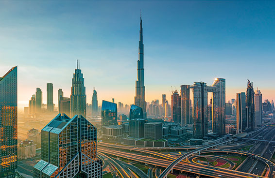 A view of the Dubai skyline at sunrise, with the Burj Khalifa towering over the city