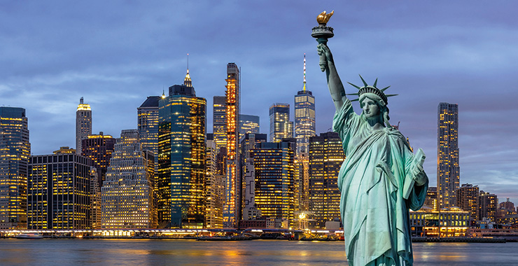 A stunning night shot of the Statue of Liberty at dusk, with the illuminated Manhattan skyline