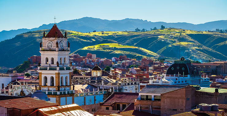 A panoramic view of the historic city center of Sucre Bolivia with the iconic clock tower and the Andes Mountains in the background