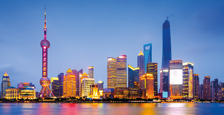 A panoramic view of the Bund skyline in Shanghai, China, at night, with the Oriental Pearl Tower illuminated