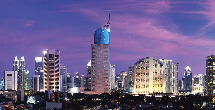 A scenic view of Jakarta skyline at night with illuminated skyscrapers and a purple sky