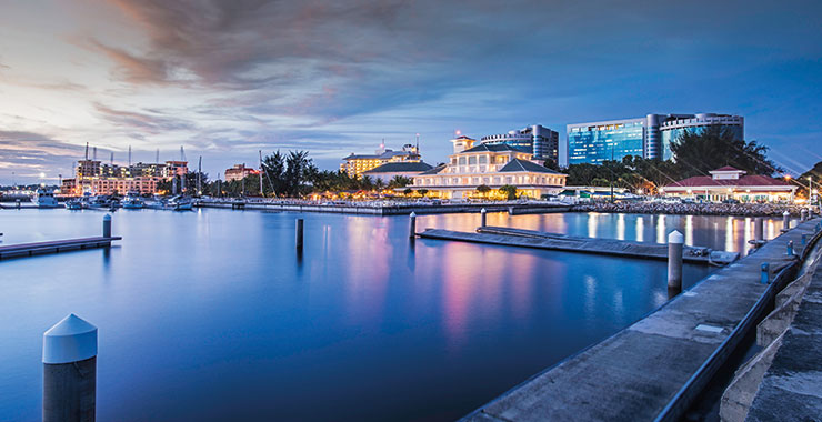 An aerial view of waterfront view of Labuan at dusk with boats docked and buildings illuminated