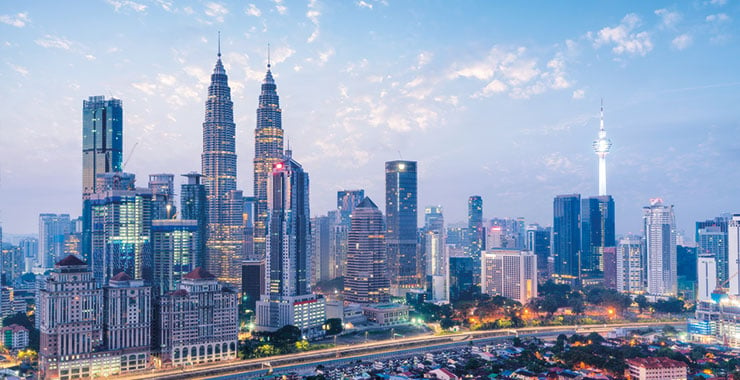 A shot of Kuala Lumpur Malaysia skyline at dusk featuring the iconic Petronas Twin Towers and Kuala Lumpur tower