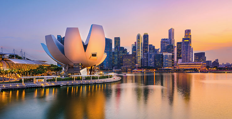 An aerial view of the Marina Bay skyline at dusk with the ArtScience Museum, and sky reflecting on the water