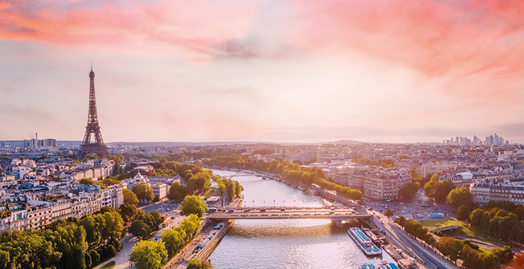 An aerial view of Paris, France, with the Eiffel Tower, Seine River, and cityscape at sunset