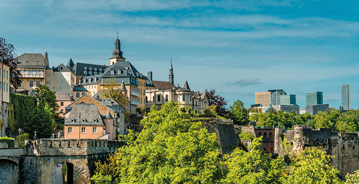 A panoramic view of Luxembourg City, showcasing the historic Grund district and the modern skyline in the background