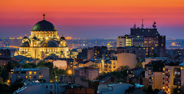 A stunning sunset shot of Belgrade, Serbia featuring the Temple of Saint Sava illuminated against the city skyline