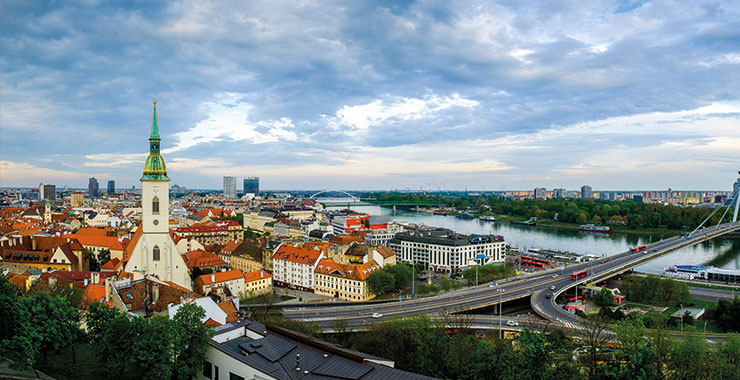 A panoramic view of Bratislava, Slovakia, with St. Martin's Cathedral, the Danube River, and the Slovak National Uprising Bridge