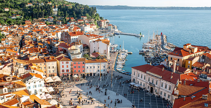 An aerial view of Piran, Slovenia, showing the colorful houses, the central square, and the harbor with boats