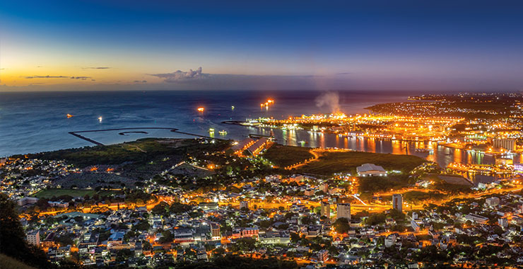 A panoramic view of Port Louis, Mauritius, at night, showing the city lights, the harbor, and the surrounding coastline