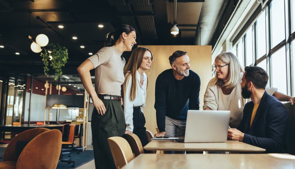 A team collaborating in a discussion at a modern workplace with laptop on the desk