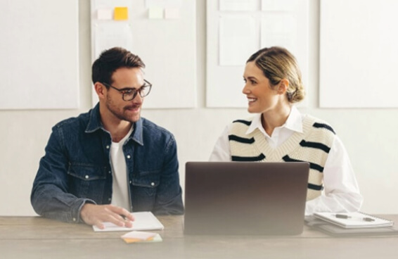 A man and woman work together at a desk demonstrating teamwork